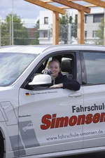 Mitarbeiterin der Fahrschule Simonsen sitzt am Steuer eines Fahrschulautos und schaut aus dem Fahrzeug.