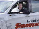 Mitarbeiterin der Fahrschule Simonsen sitzt am Steuer eines Fahrschulautos und schaut aus dem Fahrzeug.