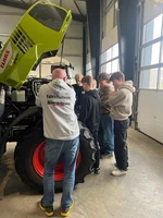 Fahrlehrer erklärt Fahrschülern die Technik und den Motorraum eines Traktors.