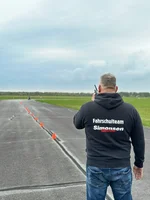 Fahrlehrer gibt einem Fahrschüler auf dem Übungsplatz per Walkie-Talkie Anweisungen.