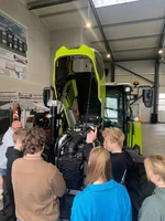 Fahrschüler besprechen mit dem Fahrlehrer den Motorraum eines Traktors.